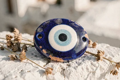 Amulette œil protecteur grec en céramique bleue cobalt posée sur pierre blanchie à la chaux, détail macro authentique