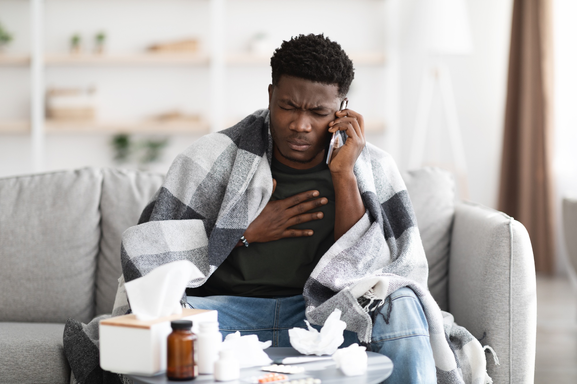 Ill black man calling doctor, touching his chest
