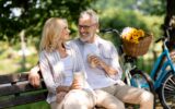 Romantic Mature Couple With Takeaway Coffee Relaxing On Bench In Summer Park
