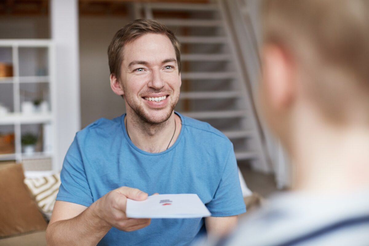 Smiling father giving birthday card to son
