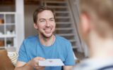 Smiling father giving birthday card to son