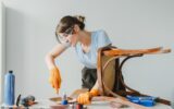 Woman using chisel restoring old wooden chair at home